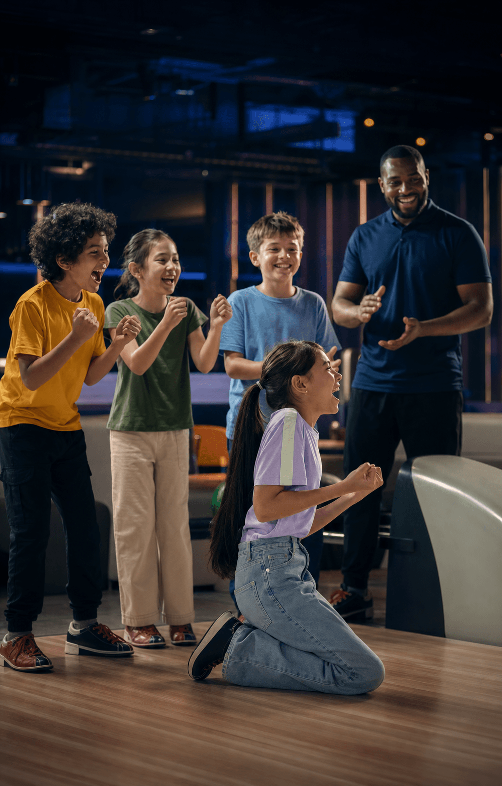 Children celebrating a bowling game with their coach